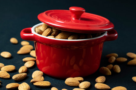 Close up of a red pot with almonds on a black background.の写真素材