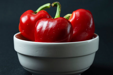 Red peppers in a white bowl on a black background. Close up.の写真素材