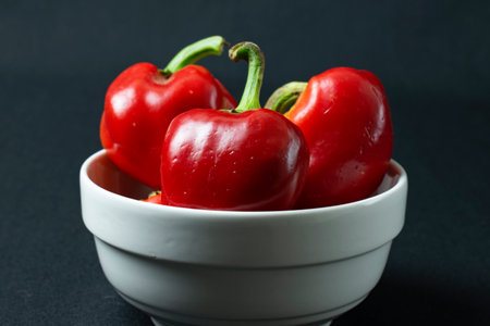 Red peppers in a white bowl on a black background close-upの写真素材
