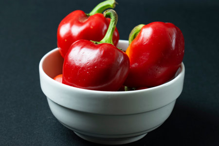 Red pepper in a white bowl on a black background. Close up.の写真素材