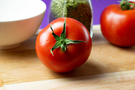 Tomatoes and spices on a cutting board on a purple background.の写真素材