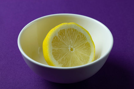 Lemon in a white bowl on a purple background, close upの写真素材