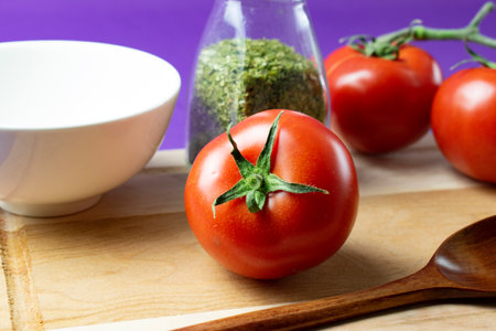 Tomatoes and spices on a cutting board with a wooden spoon.の写真素材