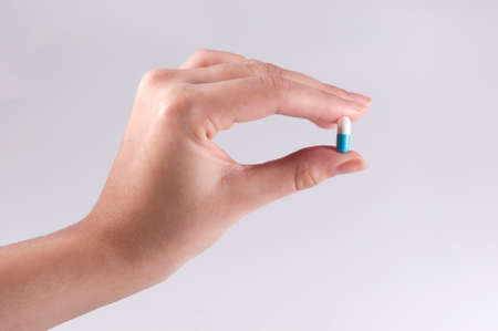 Caucasian Woman Holding a Pill on White Background / Capsules and Pills / Medicineの写真素材