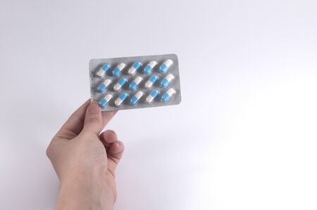 Caucasian Woman Holding a Blister Pack of Pills on White Background / Capsules and Pills / Medicineの写真素材