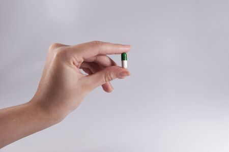 Caucasian Woman Holding a Pill on White Background / Capsules and Pills / Medicineの写真素材