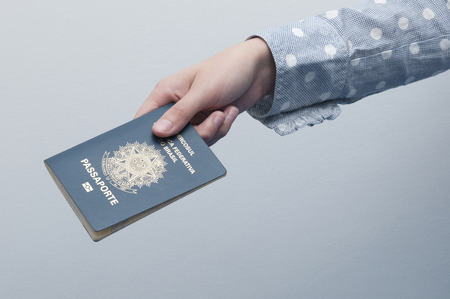 Caucasian Woman holding a brazilian passport / A passport is a government-issued document that certifies the identity and nationality of its holder for the purpose of international travel.のeditorial素材