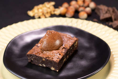 Chocolate Brownie with nuts and chocolate cream on black plate - Delicious dessertの写真素材