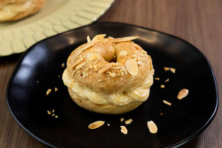 Classic dessert Paris Brest with almond on black plate / Delicious traditional french dessert