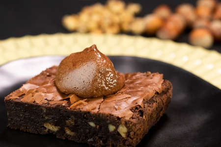Chocolate Brownie with nuts and chocolate cream on black plate - Delicious dessertの写真素材