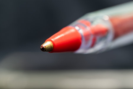 Close-up of a red ballpoint pen on a black background