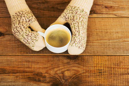Woman hands in teal gloves are holding a mug with hot coffee or cocoa.  Winter and Christmas concept.の写真素材