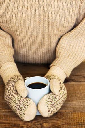 Woman hands in teal gloves are holding a mug with hot coffee or cocoa.  Winter and Christmas concept.の写真素材