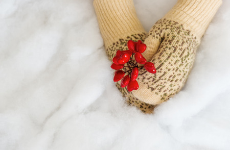 Woman hands in light teal knitted mittens are holding red heart on snow background. Winter, Valentines and Christmas concept.の写真素材