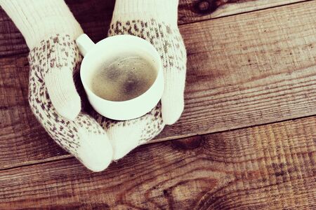 Woman hands in teal gloves are holding mug with hot coffee or cocoa. Winter and Christmas concept.の写真素材