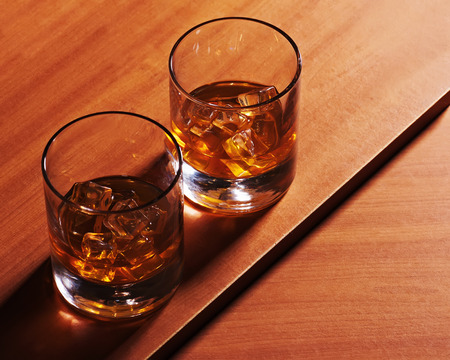 Highball whiskey glass with ice on wooden background. Closeup.の写真素材