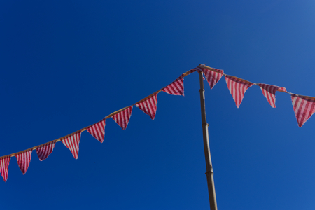 Striped Flag banner supported by a bamboo post stretching across a bright blue sky