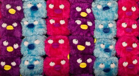 purple,pink and blue rows of baby bird plush toys, which are a carnival prize.