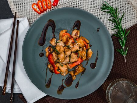 Chicken with soy sauce and chopsticks on blue plate. Chinese dish, spicy lunch, top view.