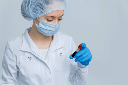 Nurse in medical mask analyses blood sample for Coronavirus testing in blue tones. MERS Wuhan, China.の写真素材