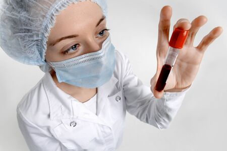 Isolated scientist on a white background analyzes a test tube with a blood sample for Coronavirus testing.の写真素材