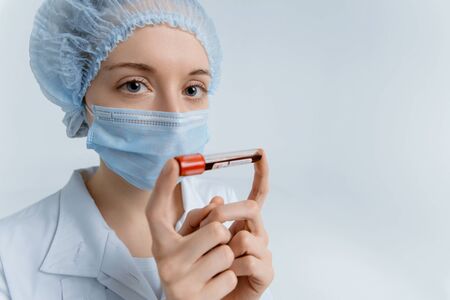 Doctor wearing medical mask holds test tube with blood sample for Coronavirus testing in blue tones. Epidemic Middle East Respiratory Syndromeの写真素材