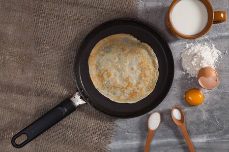 Cooking pancakes for Maslenitsa breakfast. A pancake on hot pan with ingredients.の写真素材