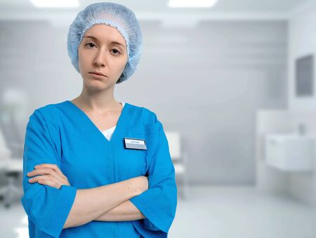 Doctor in blue medical uniform stands in the medical ward and looks sternly at camera.の写真素材