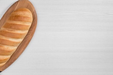 Loaf of bread on wooden cutting board on white background top view.の写真素材