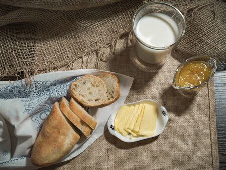 Breakfast at dawn in the village with milk, bread, butter and orange jam.の写真素材