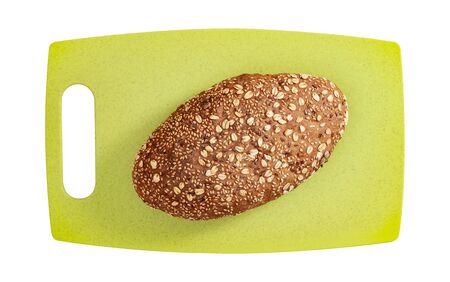 Isolated bread with seeds and flakes on green cutting board on white