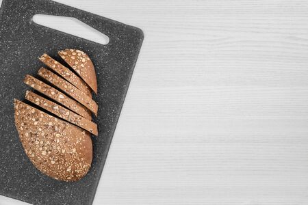 Sliced bread with seeds and flakes on gray cutting board on whiteの写真素材