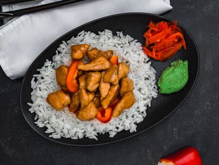 Rice with chicken, wasabi, ginger and chopsticks on white napkin on black background. Chinese dish. Horizontal shot.の写真素材