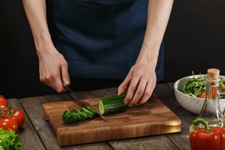Woman cooking fresh healthy salad. Female hands cutting vegetables on board on wooden table. Diet concept for healthy lifestyle.の写真素材