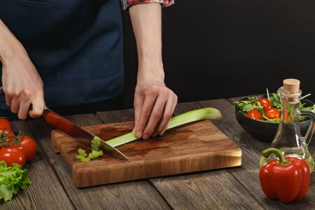 Woman cooking fresh salad. Female hands cutting vegetables on board on wooden table.の写真素材
