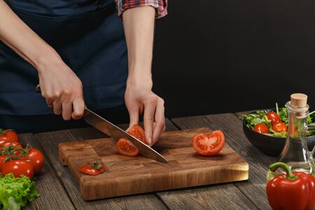 Woman cooking fresh healthy salad. Female hands cutting vegetables on board on wooden table. Diet concept for healthy lifestyle.の写真素材