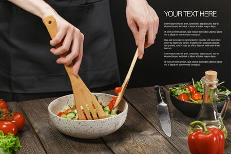 Woman cooking fresh vegetable salad on wooden table. Healthy vegetarian lifestyle.の写真素材