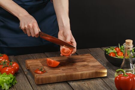 Woman cooking fresh healthy salad. Female hands cutting vegetables on board on wooden table. Diet concept for healthy lifestyle.の写真素材