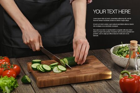 Woman cooking fresh salad. Female hands cutting vegetables on board on wooden table.の写真素材