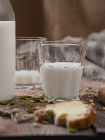 Breakfast in the country with milk and whole wheat bread. Bitten loaf of bread with butter on an old vintage planked wooden table with canvas.の写真素材