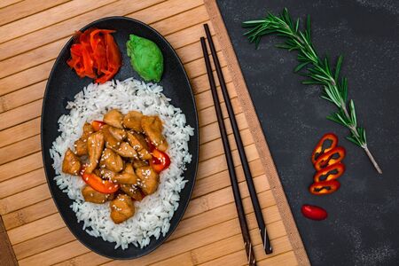 Chicken with rice, wasabi and ginger on wooden board on black background. Asian dish, oriental cuisine.の写真素材