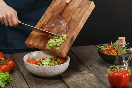 Woman cooking fresh healthy salad. Female hands cutting vegetables on board on wooden table. Diet concept for healthy lifestyle.の写真素材