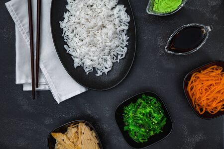 Rice with Korean carrots, soy asparagus, chuka, wasabi, soy sauce and white napkin on black background top view.の写真素材