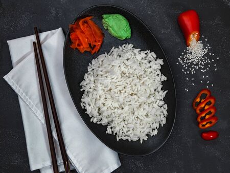 Rice with pepper, wasabi, ginger and scattered sesame seeds on white napkin on black background. Chinese dish. Horizontal shot.の写真素材