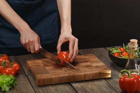Woman cooking fresh healthy salad. Female hands cutting vegetables on board on wooden table. Diet concept for healthy lifestyle.の写真素材