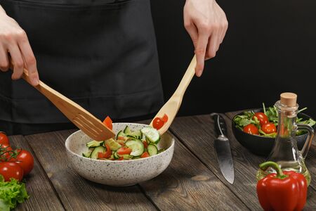 Woman cooking fresh healthy vegetable salad on wooden table. Diet concept for healthy lifestyle.の写真素材