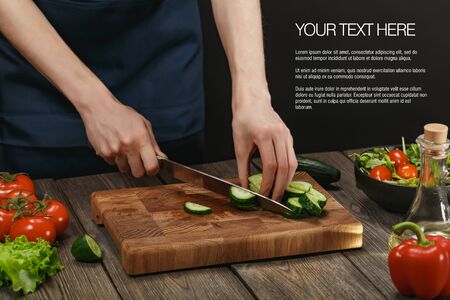 Woman cooking fresh salad. Female hands cutting vegetables on board on wooden table.の写真素材
