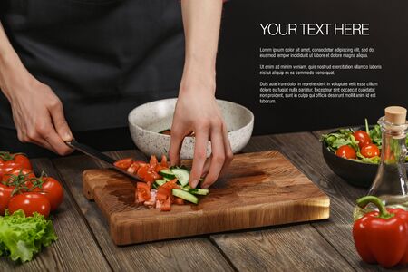 Woman cooking fresh healthy salad. Female hands cutting vegetables on board on wooden table. Diet concept for healthy lifestyle.の写真素材