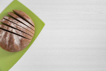 Loaf of bread on green cutting board on white background top view.の写真素材
