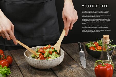 Woman cooking fresh vegetable salad on wooden table. Healthy vegetarian lifestyle.の写真素材